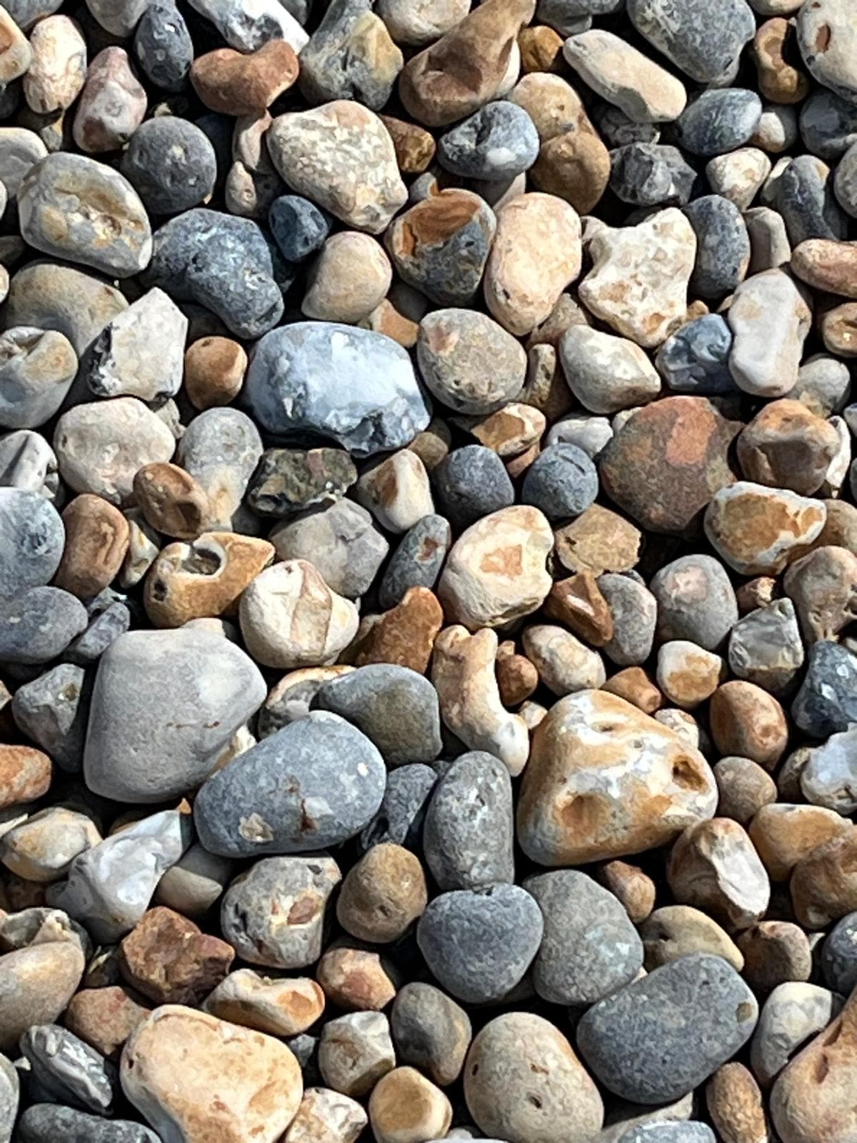 Smooth beach pebbles in soft grey, sand and blue tones